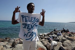 A migrant shouts a slogan as he wears a Tee Shirt with the message, "Open The Way" as he stands on the seawall at the Saint Ludovic border crossing on the Mediterranean Sea between Vintimille, Italy and Menton, France, June 14, 2015. On Saturday, some 200 migrants, principally from Eritrea and Sudan who attempted to cross the border, were blocked by Italian police and French gendarmes. REUTERS/Eric Gaillard - RTX1GG1X